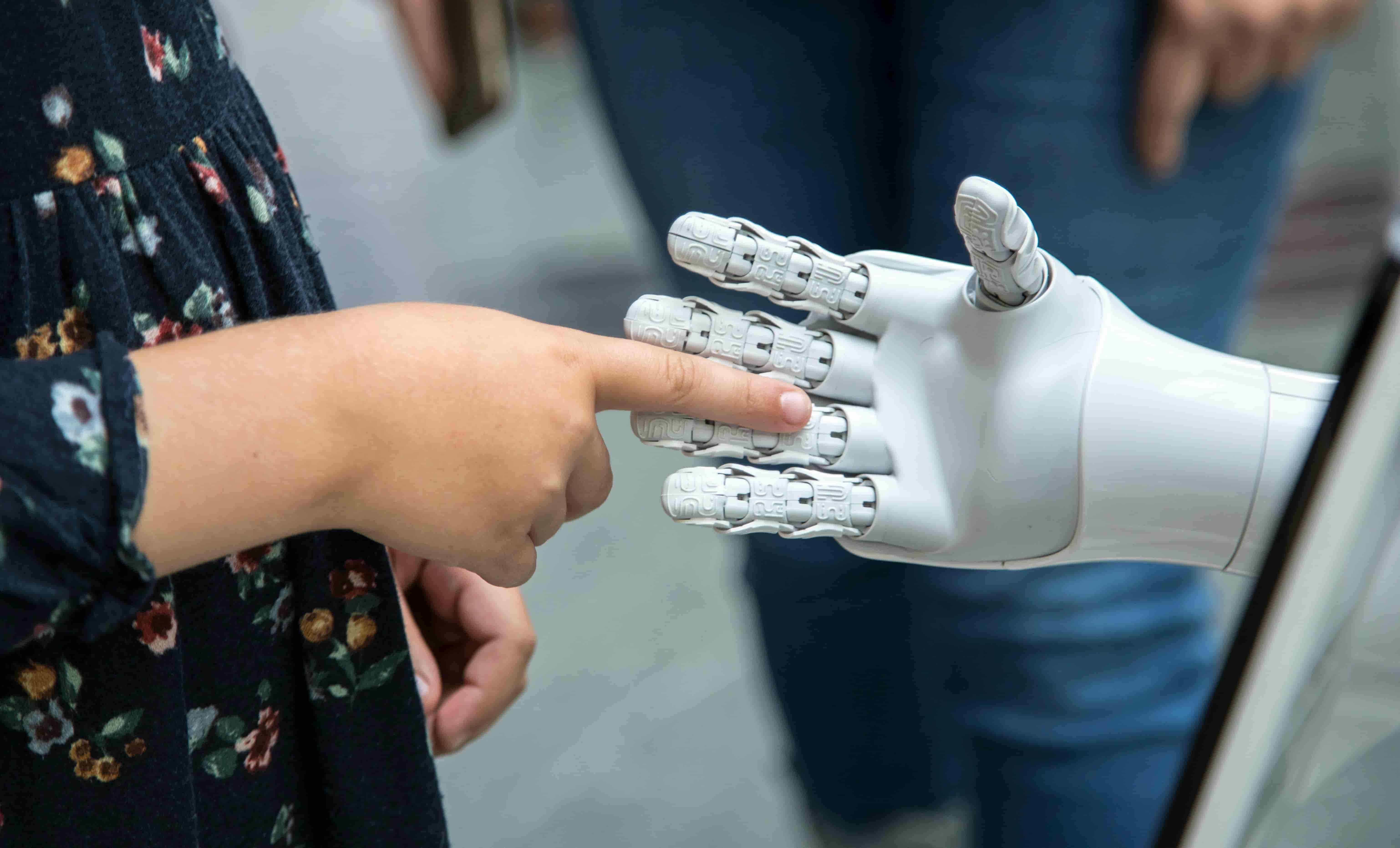 A close up view of a childs hand shaking Rob the robots hand.